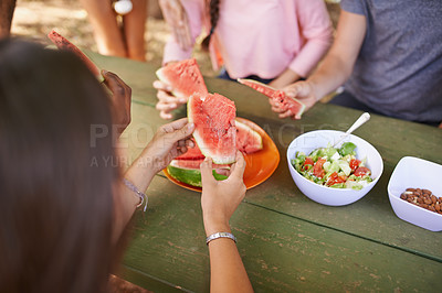 Buy stock photo High angle shot of a group of friends eating watermelon while on a picnic at the park