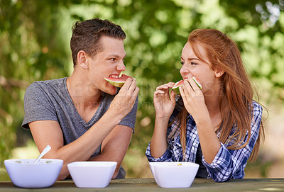 Buy stock photo Shot of two teenagers eating watermelon while on a picnic at the park