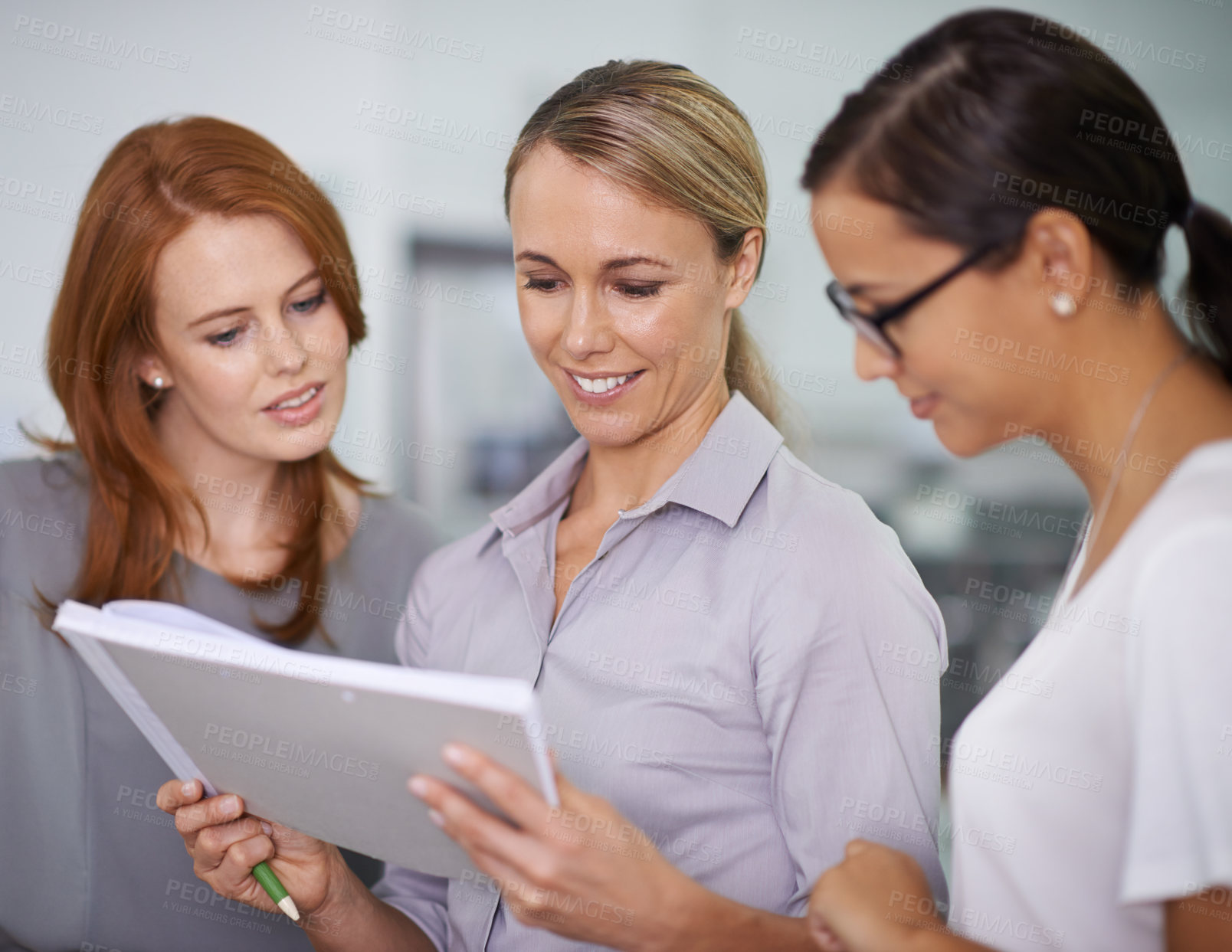 Buy stock photo Team leader showing strategy ideas on paper and meeting with creative colleagues in office. Young, motivated and interested group of business women standing together and using paperwork to brainstorm