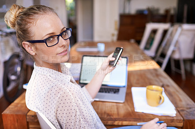 Buy stock photo Woman, phone and laptop on table in home office for remote work, startup and text online with coffee.Young person and smile with tech for internet, research and scroll for message indoor on blurred 