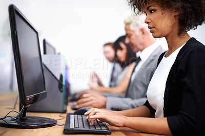 Buy stock photo Cropped shot of an attractive young working at a desk with her colleagues in the background