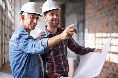 Buy stock photo Shot of two male architects wearing hardhats inspecting a building