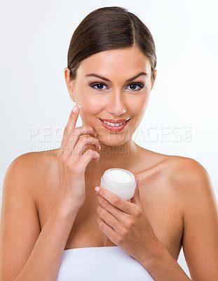 Buy stock photo Skincare, cream and dermatology for woman in studio with product for moisture, smooth and clean on face. Young person and smile with finger on cheek with lotion for beauty, soft and wellness  