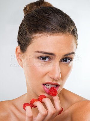 Buy stock photo Portrait, beauty and raspberry fingers with woman in studio on white background for health or cosmetics. Face, makeup and wellness with confident young model eating fruit for diet or nutrition