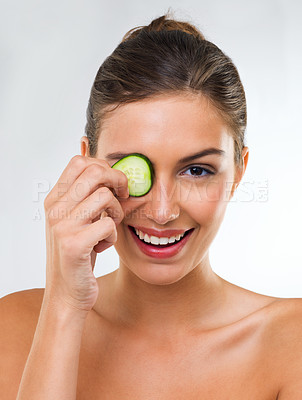 Buy stock photo Portrait of a gorgeous young woman holding a slice of cucumber over her eye