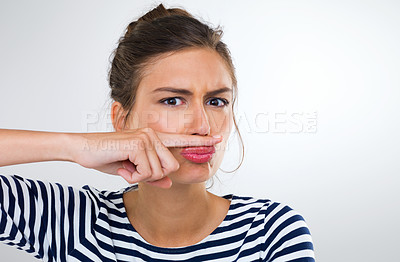 Buy stock photo Portrait of a beautiful young woman using her finger to make a moustache