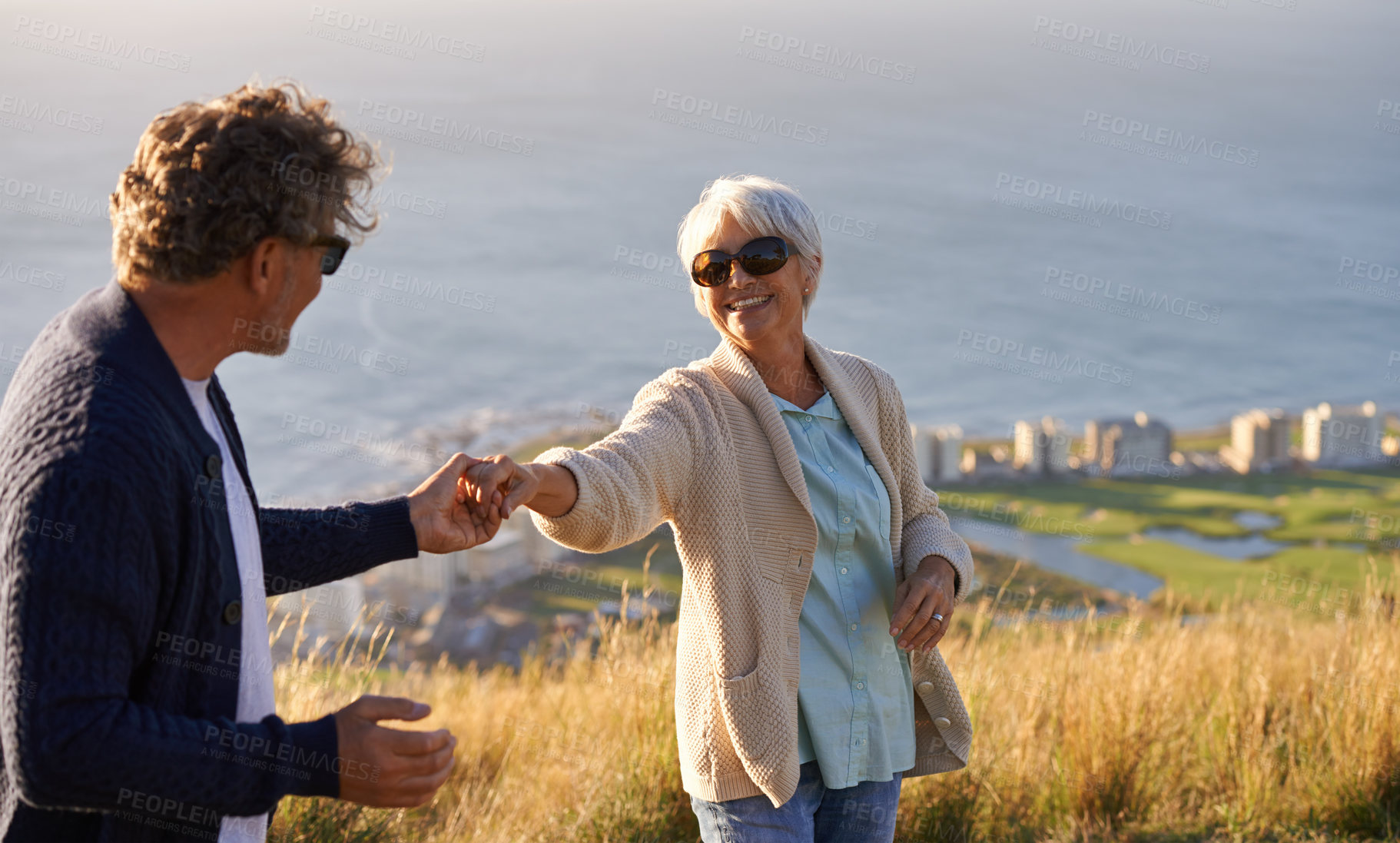 Buy stock photo Happy, vacation and couple outdoor in dance on hill or mountain in Cape Town and holding hands with love. Mature, people and embrace with kindness on holiday adventure in nature and relax together