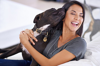 Buy stock photo Shot of an attractive young woman enjoying a cuddle with her dog at home