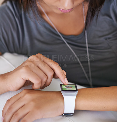 Buy stock photo Cropped shot of a young woman looking at her smartwatch