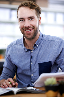 Buy stock photo Portrait of a handsome young man paging through a magazine in the office