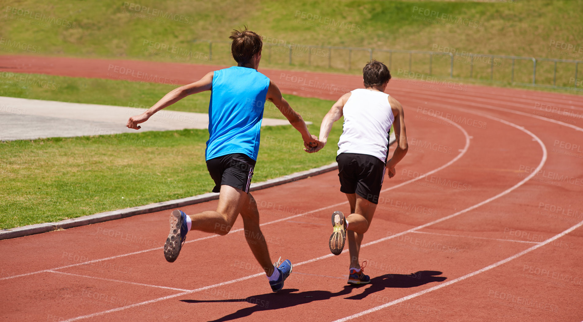 Buy stock photo Rearview shot of two athletes running in a relay race