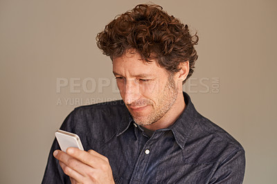 Buy stock photo Mature man, smartphone and texting in studio for thinking, reading or scroll for search on web by background. Person, phone and check for email, notification or post on social network with mobile app