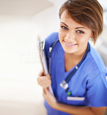 Buy stock photo Portrait of an attractive young doctor in scrubs holding a clipboard