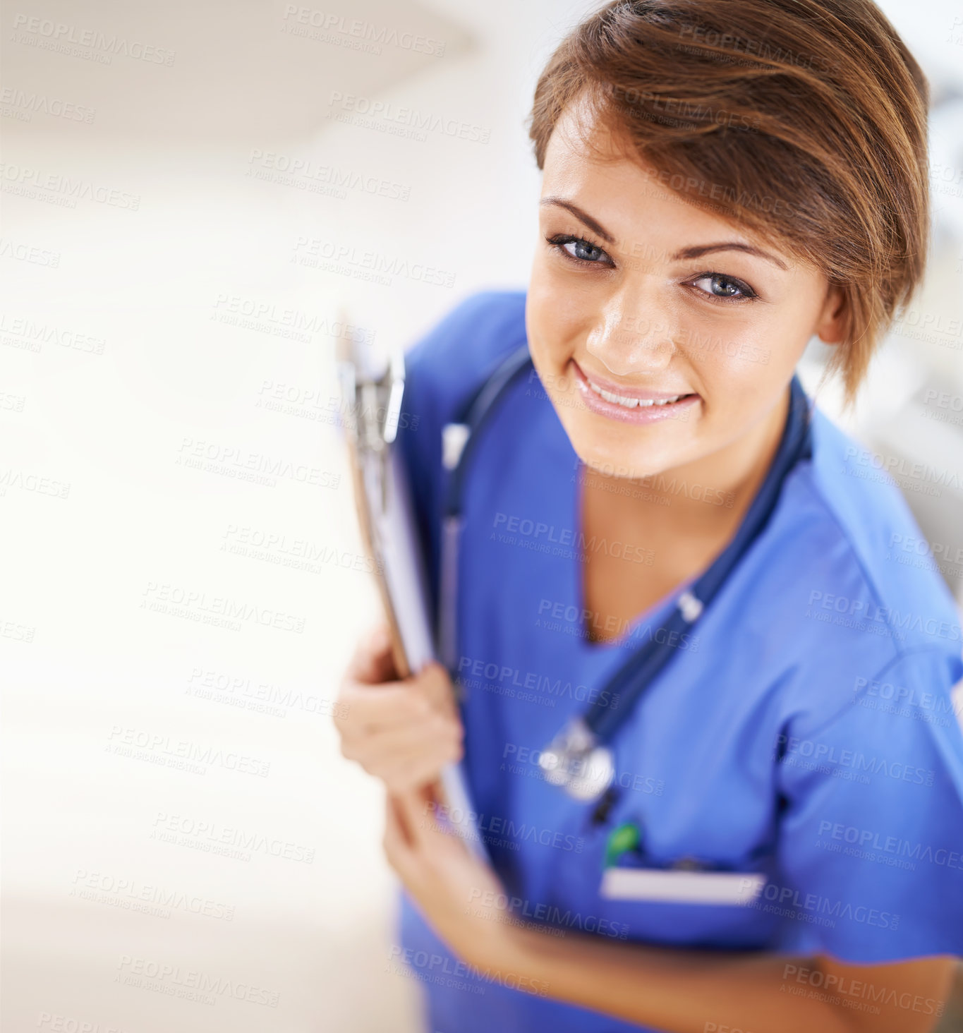 Buy stock photo Portrait of an attractive young doctor in scrubs holding a clipboard