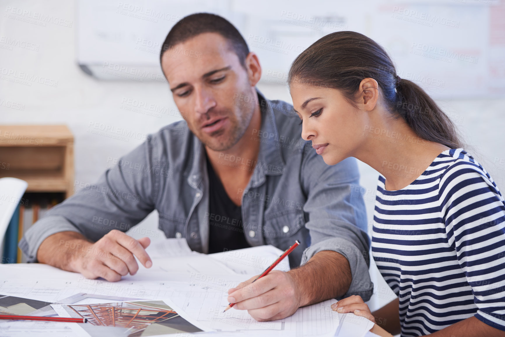 Buy stock photo Cropped shot of a man and young woman discussing blueprints