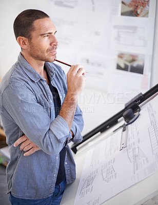 Buy stock photo Cropped shot of an architect looking thoughtful beside his drawing table