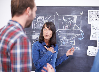 Buy stock photo Shot of two coworkers planning a storyboard on a blackboard
