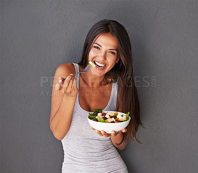 Buy stock photo Portrait of a healthy young woman eating a salad against a gray background