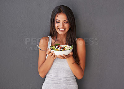 Buy stock photo Healthy young female eating her fresh food salad bowl. Smiling beautiful woman holding and enjoying eating her clean green diet dish of vegetables as part of her vegan wellness lifestyle 