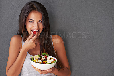 Buy stock photo Portrait of an attractive young woman eating a salad against a gray background