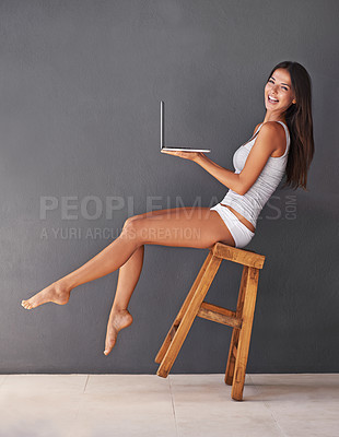 Buy stock photo Laptop, portrait and woman on chair to balance in studio with gray wall background for social media. Computer, smile and underwear with happy young person on stool to relax for blogging or streaming
