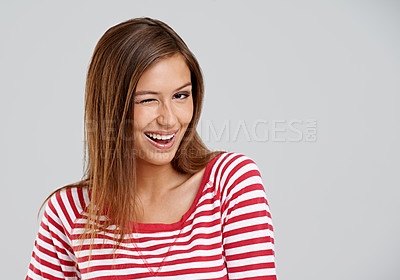Buy stock photo Wink, portrait and girl in studio with smile for fun mood, positive attitude and mockup space. Playful, cute and happy gen z woman on white background for wellness, relax and flirt with emoji face