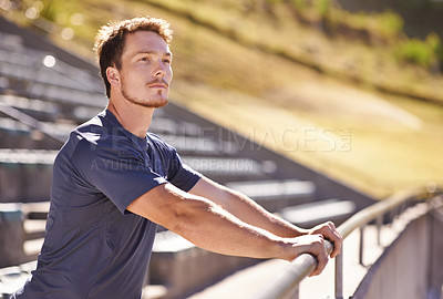 Buy stock photo Shot of a handsome young man stretching at an athletics arena