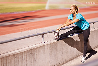 Buy stock photo Shot of an attractive young runner stretching out on the track