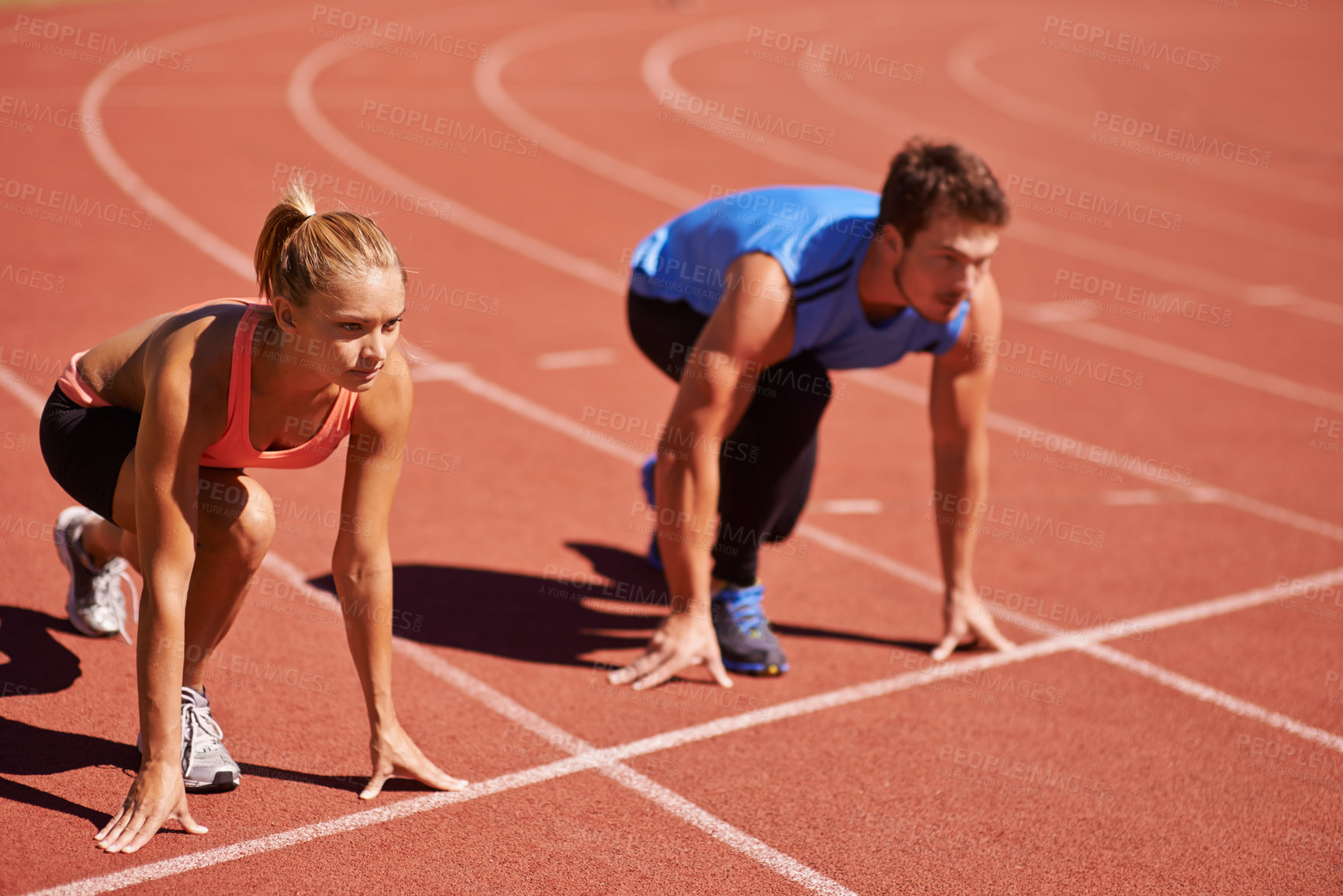 Buy stock photo Shot of two young people getting ready to race on an athletics track
