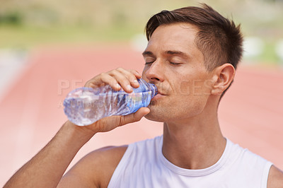 Buy stock photo Shot of a handsome young athlete taking a drink from a water bottle