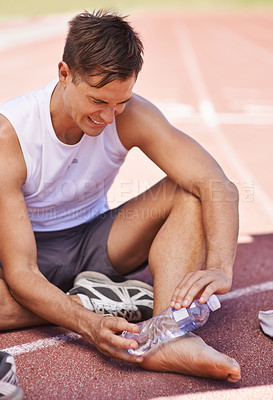 Buy stock photo Injury, outdoor and man with water bottle on feet for exercise, running or workout pain at a sports stadium. Athlete person with muscle problem, accident or burnout while training for body fitness