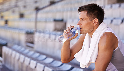 Buy stock photo Stadium, relax man or athlete for drinking water and commitment to fitness for sprinting competition. Person, competitive and runner with thinking in sport, planning and health drink for performance