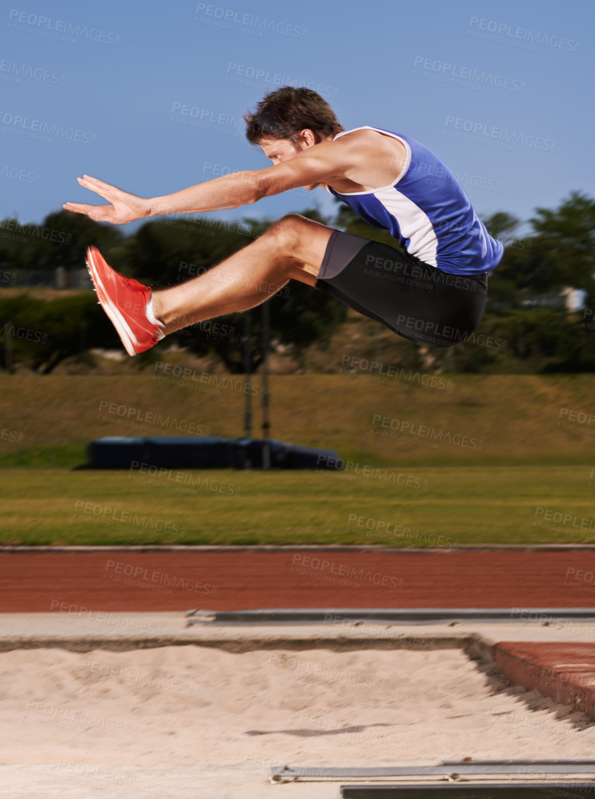 Buy stock photo Full length shot of a handsome young athlete doing long jump