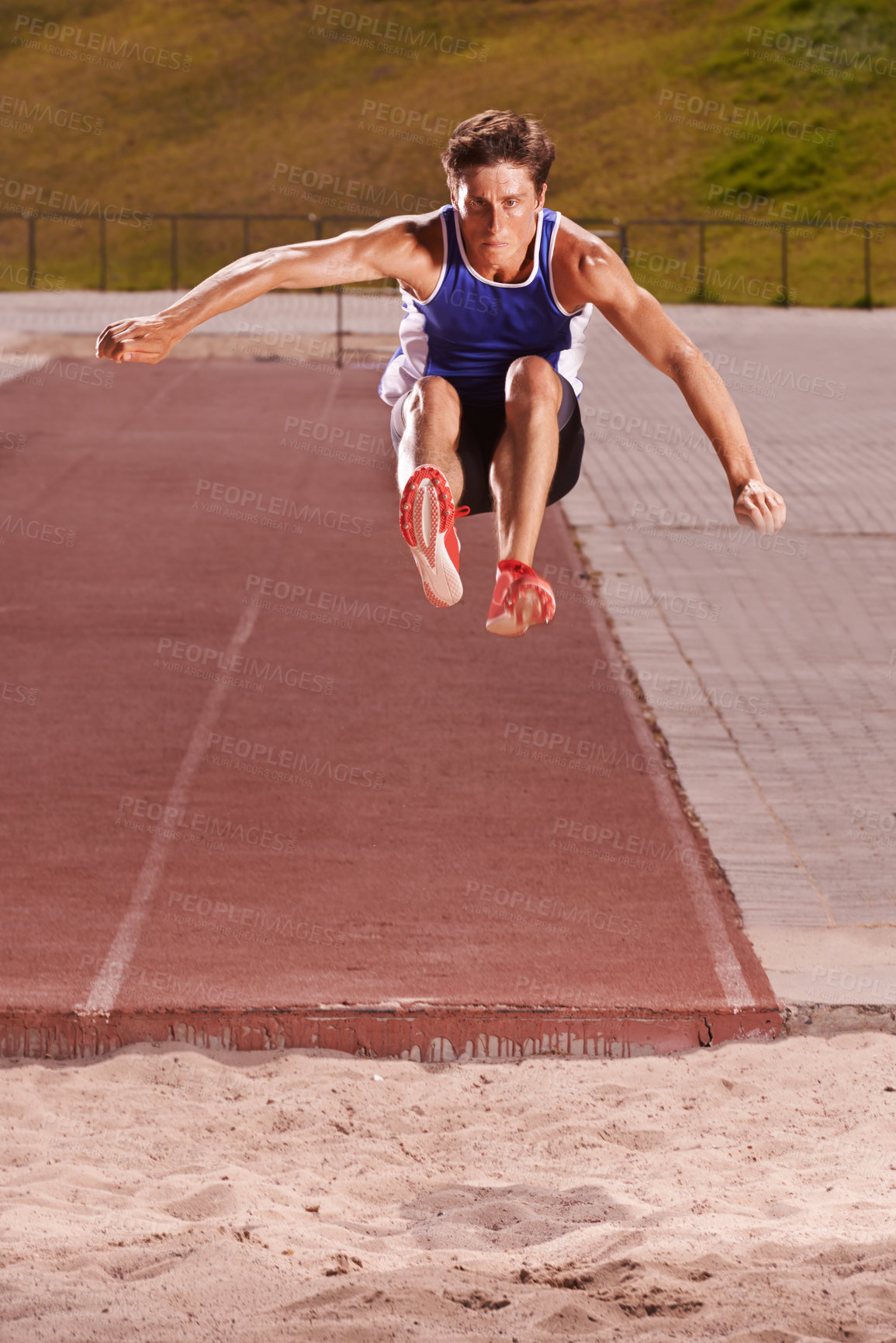 Buy stock photo Full length shot of a handsome young athlete doing long jump