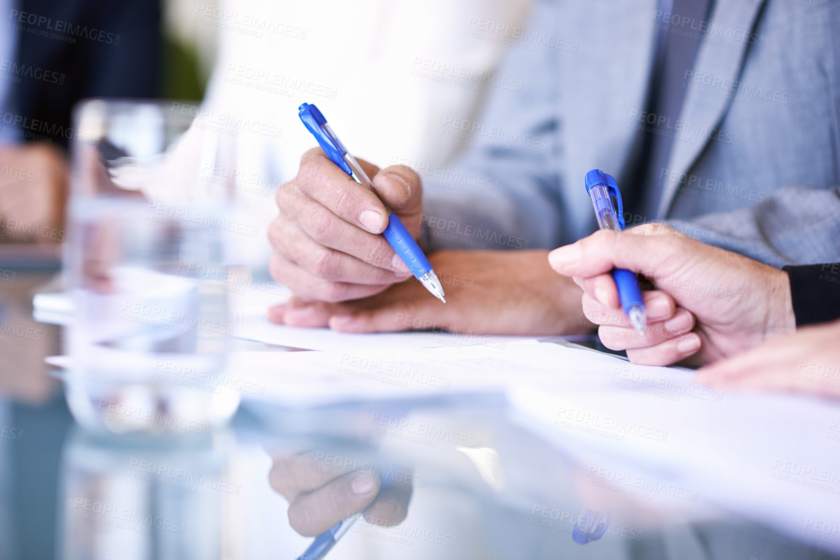 Buy stock photo Cropped view of a group of businesspeople working at a table on some documents