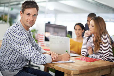 Buy stock photo Man, portrait and smile at desk with meeting for business or creative company, planning and teamwork. Male person or designer, office and collaboration for startup agency, paperwork and documents.