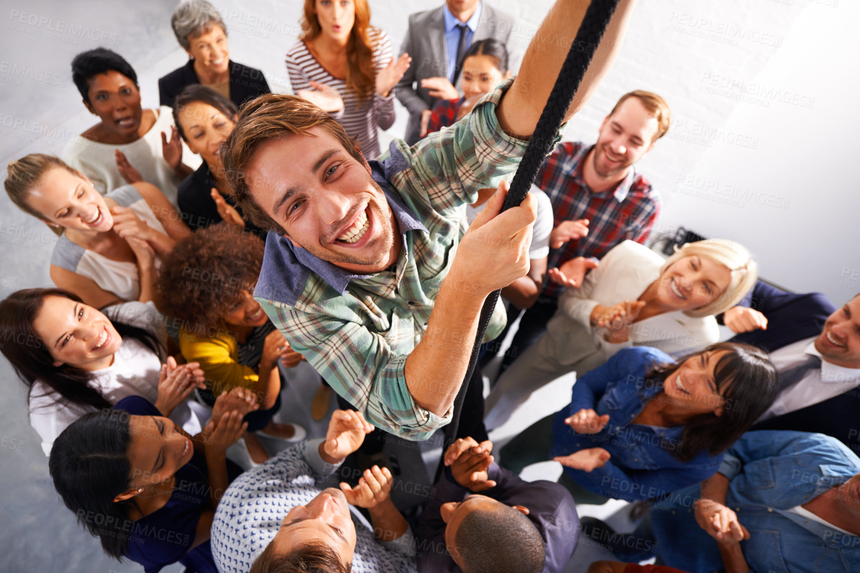 Buy stock photo Shot of a diverse group of business people watching a young man climb a rope