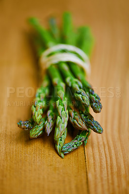 Buy stock photo Asparagus, closeup and counter for nutrition, wellness or organic diet on wood countertop. Vegetable, health or produce for eating, gourmet and meal or cuisine with vitamins or fibre for weight loss