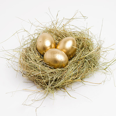 Buy stock photo Studio shot of a clutch of golden eggs laying in a nest