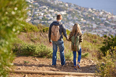 Buy stock photo Rear view shot of a young couple walking down a hiking trail