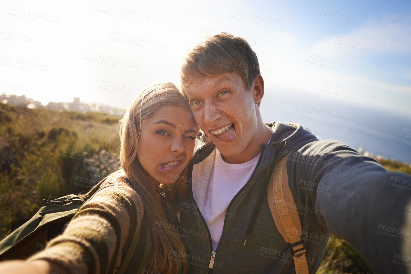 Buy stock photo Funny, face and hiking couple with selfie in nature for bonding, fun or goofy memory at sunset. Happy, love and people embrace for silly profile picture, photography or social media travel blog photo