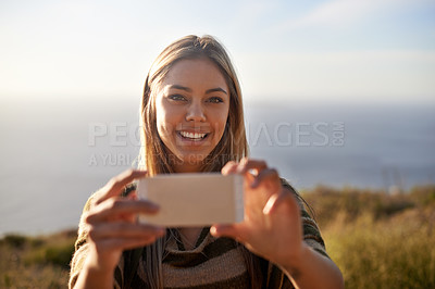 Buy stock photo Portrait of an attractive young woman holding up her cellphone to take a photo outdoors