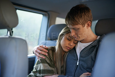 Buy stock photo Shot of a tired young couple sitting together in the back seat of a car