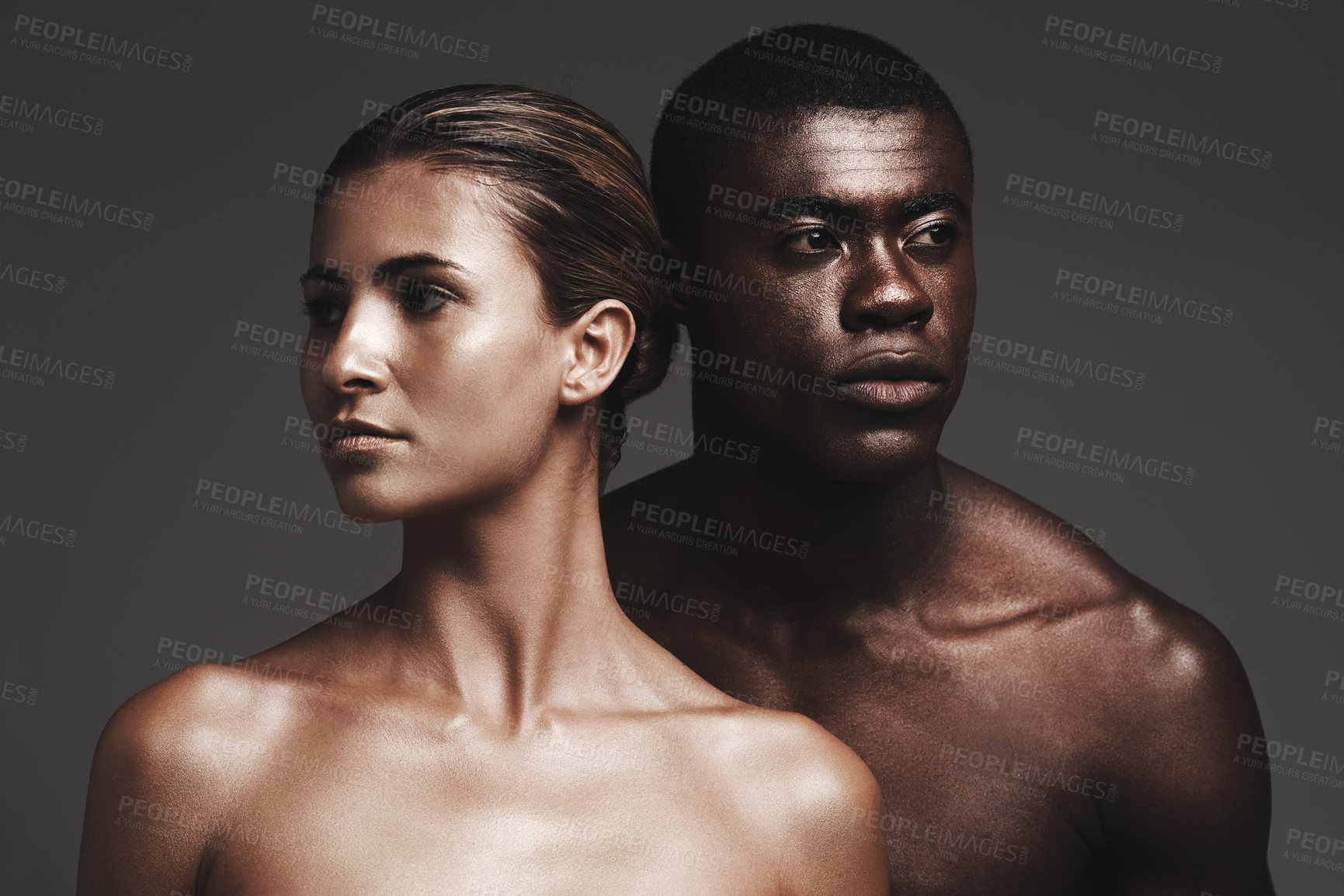 Buy stock photo Shot of a beautiful couple posing in a studio - gray background