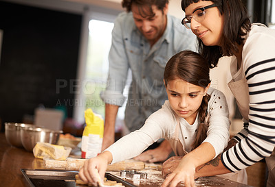 Buy stock photo Mother, father and girl with baking cookies in kitchen with pan, happiness and teaching with support. Family, parents and child with helping, learning and bonding with cooking for dinner and snack