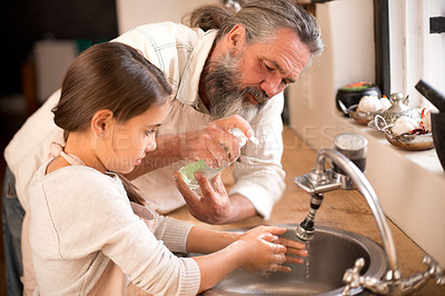 Buy stock photo Shot of a girl washing her hands in the kitchen sink as her grandfather stands by