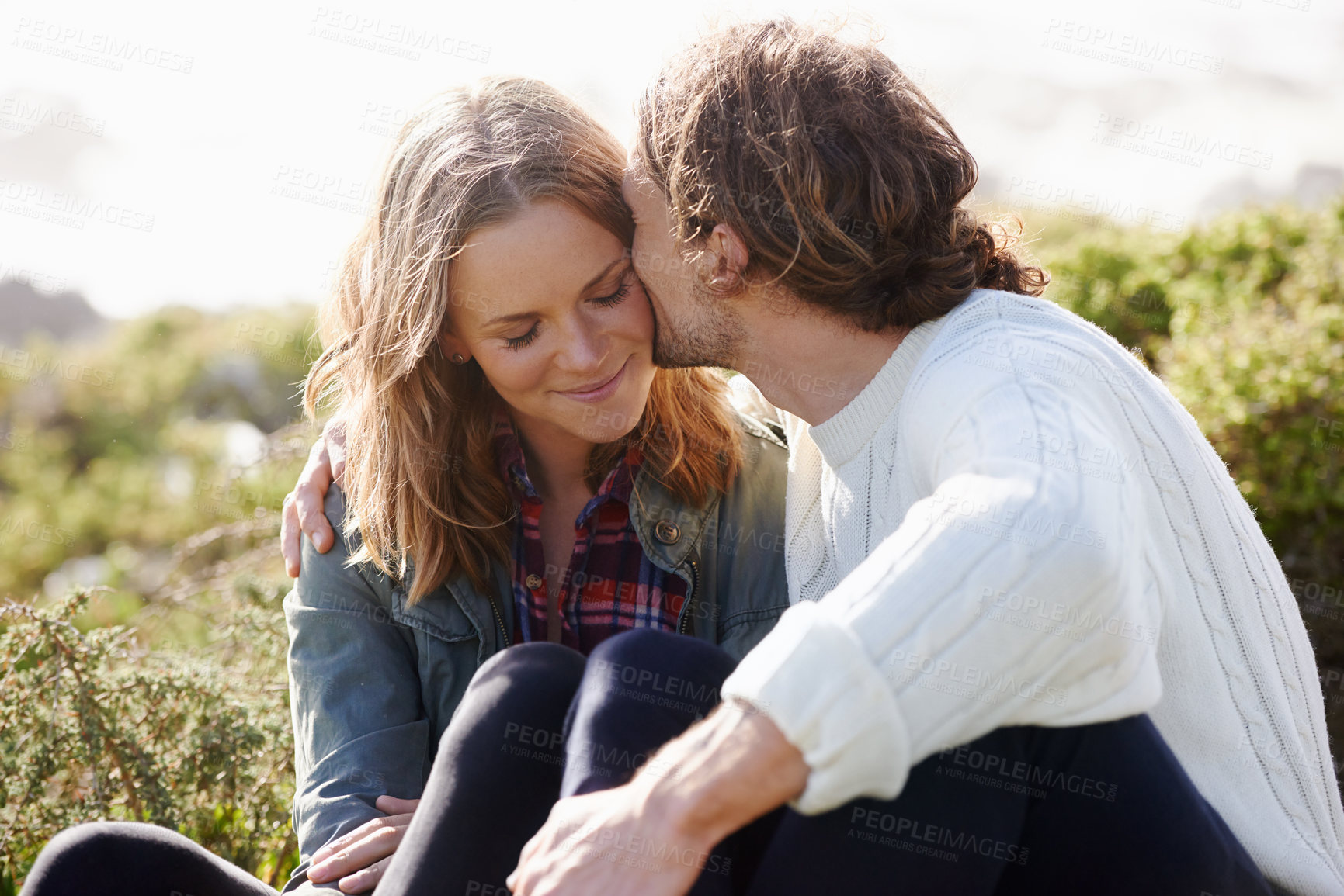 Buy stock photo Kiss, outdoor and couple with love, sunshine and relaxing with holiday with summer or honeymoon. Nature, relationship or man with woman or happiness with vacation or journey with adventure or date