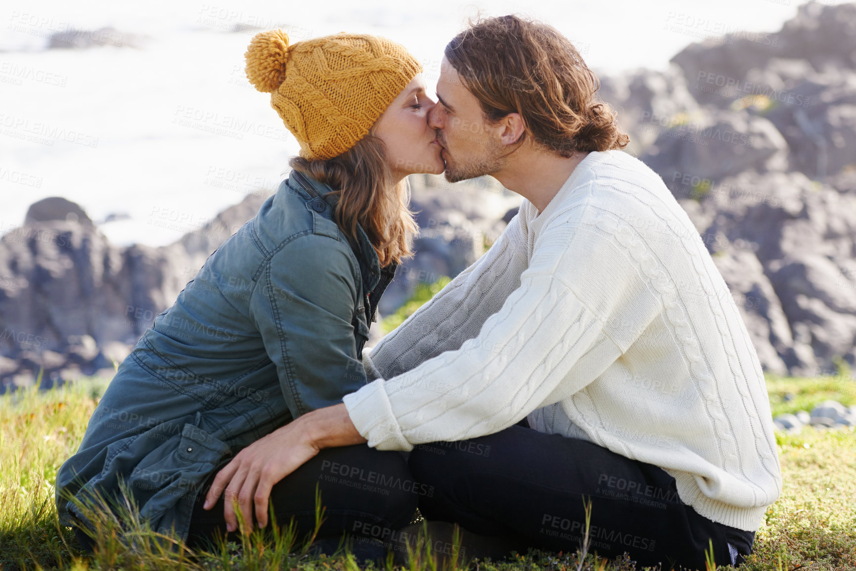 Buy stock photo Affection, couple and kissing in nature or outdoor on grass, hilltop and scenery or passionate people. Love, care and romantic date or winter vacation, holiday and relationship together in Sweden