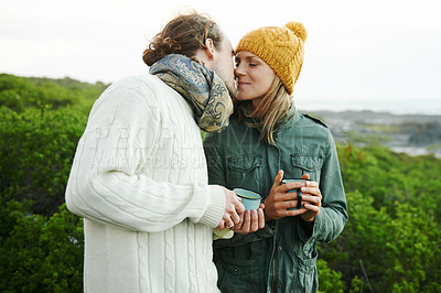 Buy stock photo Kiss, couple and drinking coffee in nature on holiday, vacation or travel together on adventure for hiking in winter. Trekking, man and woman with tea cup outdoor in the countryside, love and romance
