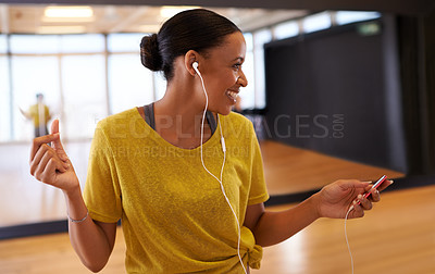 Buy stock photo An attractive young dancer listening to music on her headphones in a dancel studio